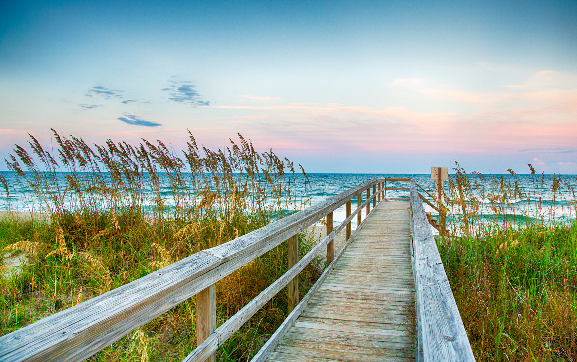There is a wooden walkway leading to the ocean.