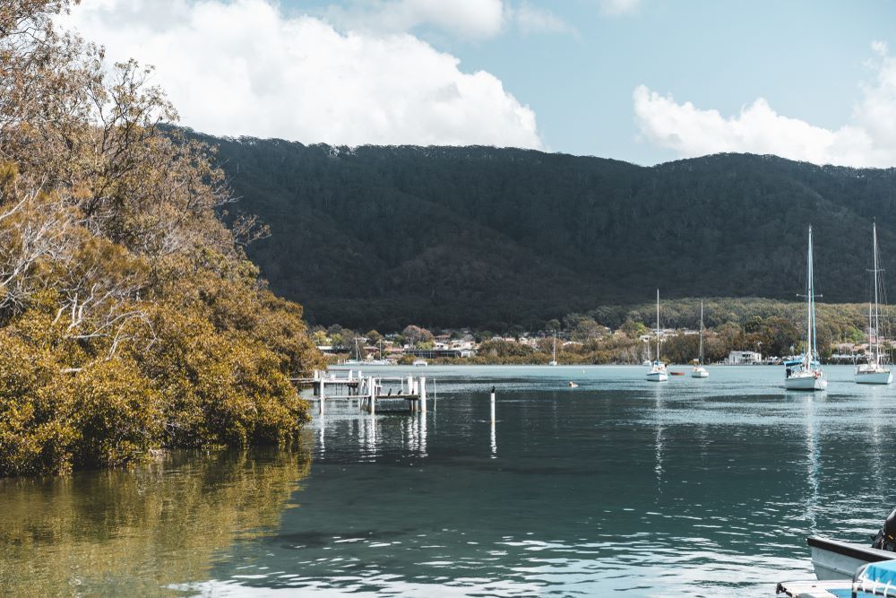 A Body of Water With Boats in It and Mountains in the Background — PH Power in Laurieton, NSW