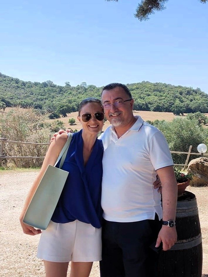 Owners of Agriturismo Lo Scalandrino, in Tuscany, cheerfully enjoying the scenic olive groves and rolling hills.