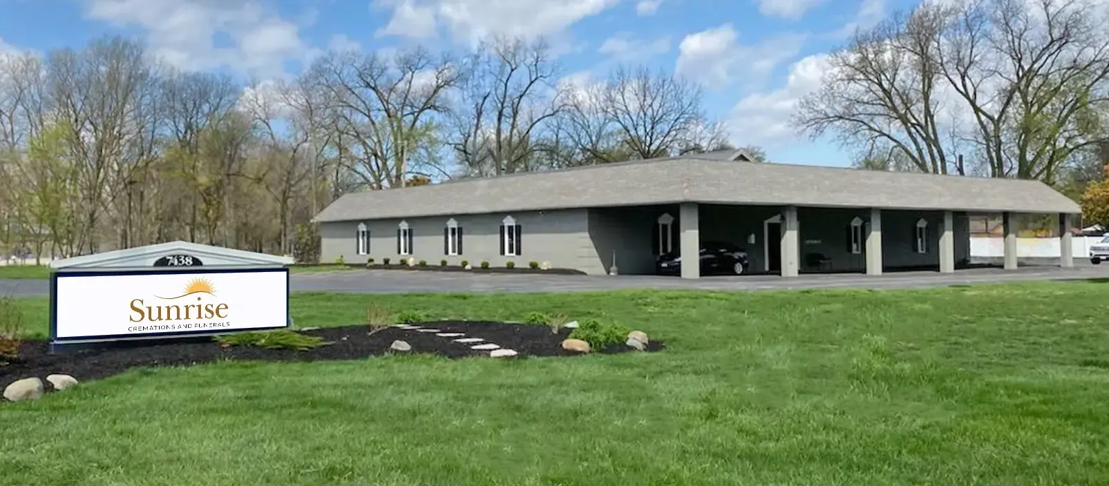 Sign for Silurian Funeral Home in front of a gray building and green lawn, with trees in the background.