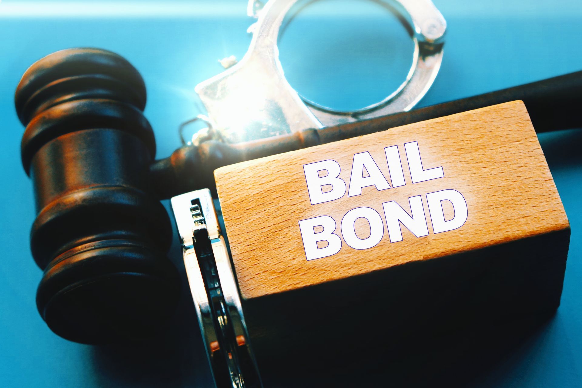 Judge's gavel and handcuffs with a wooden block with the words bail bond.