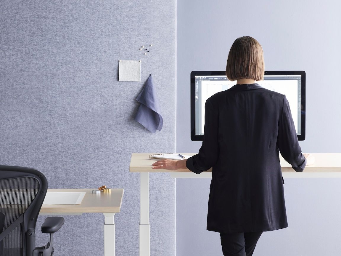 Image of woman standing at a sit / stand desk to remain flexible
