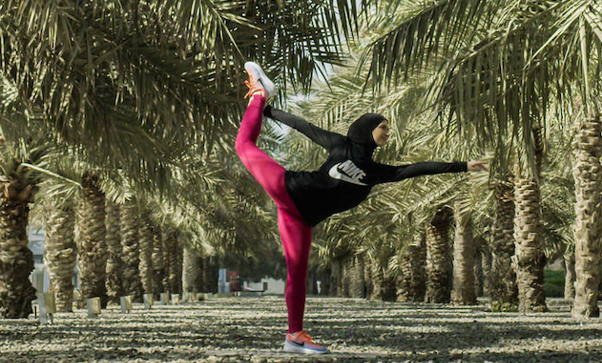 Woman stretching outdoors in between rows of palm trees