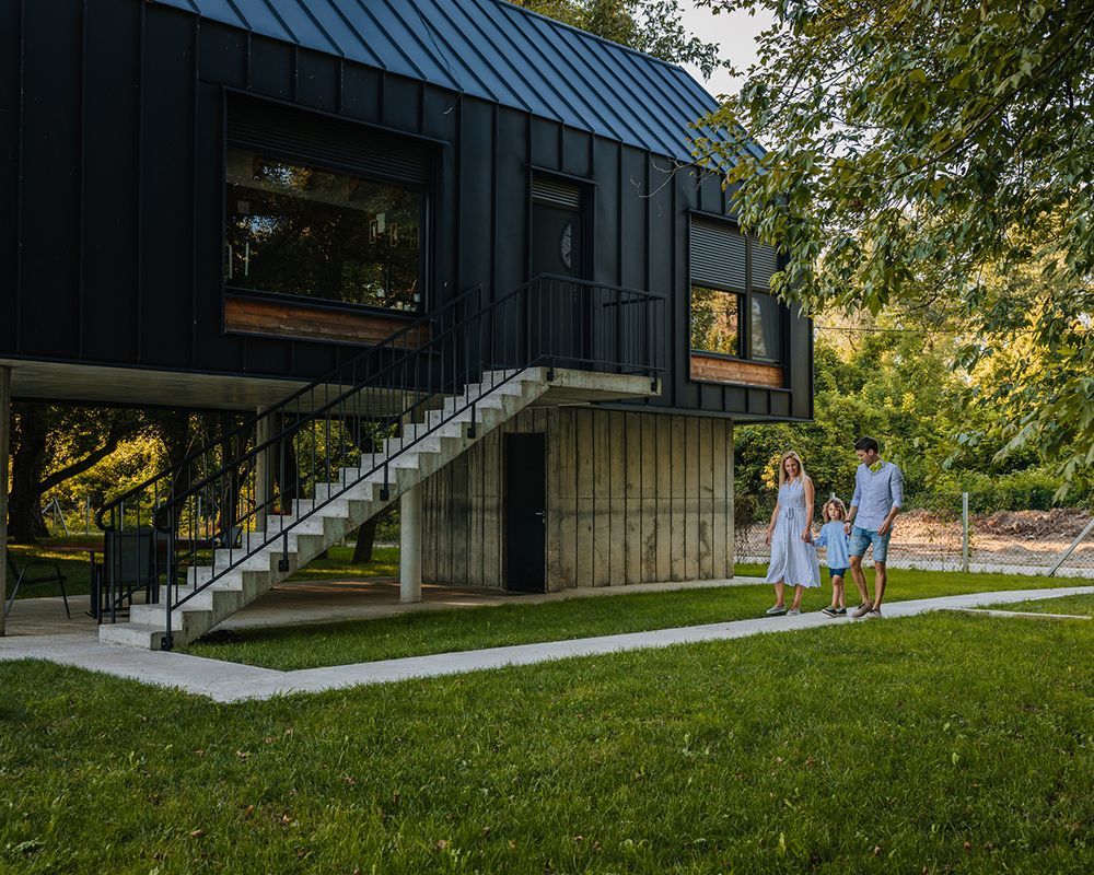 A couple walks towards a contemporary barndominium in Jefferson City, MO, along a scenic path lined 