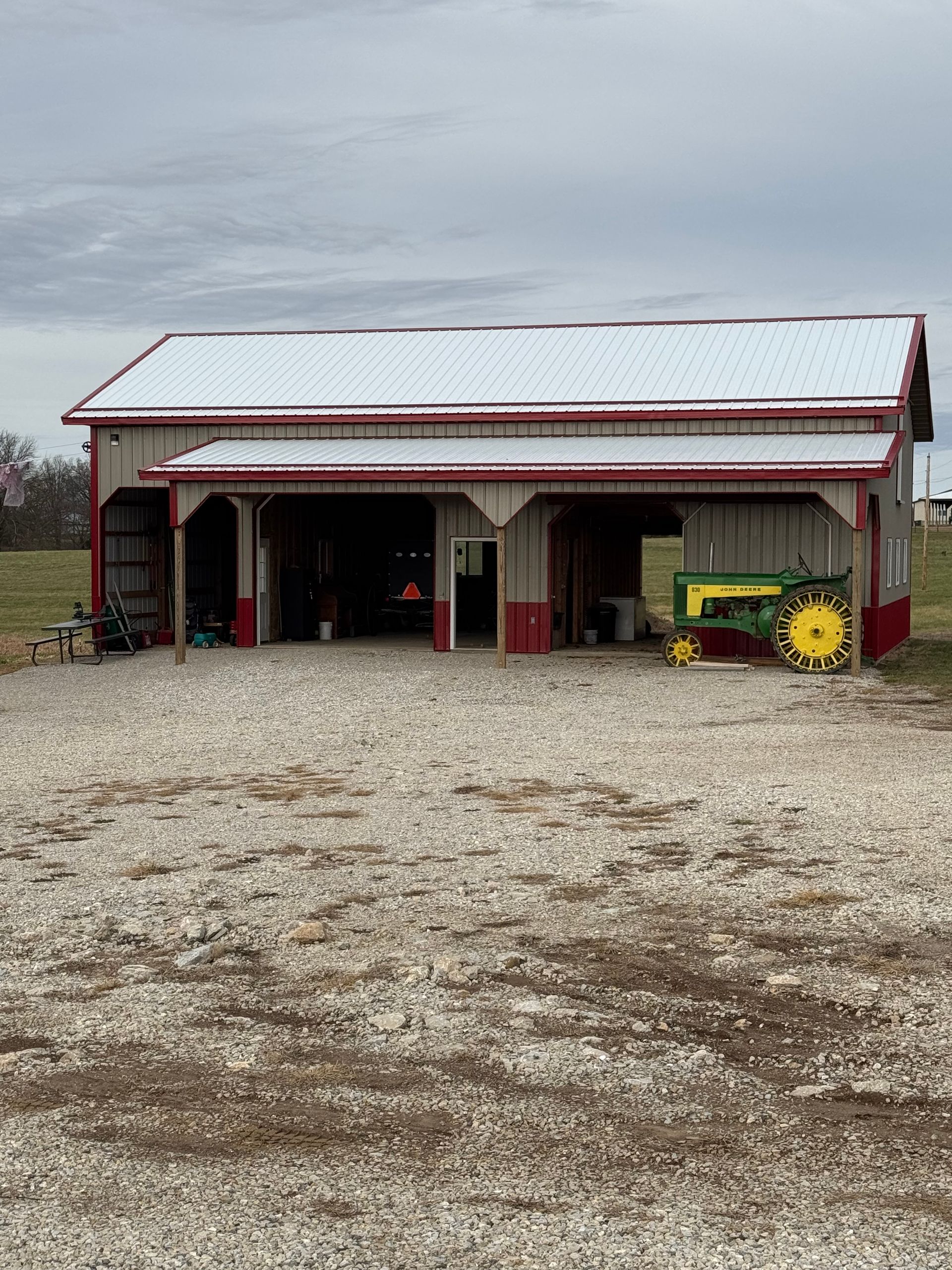 Barn with red trim and a John Deere tractor parked outside.