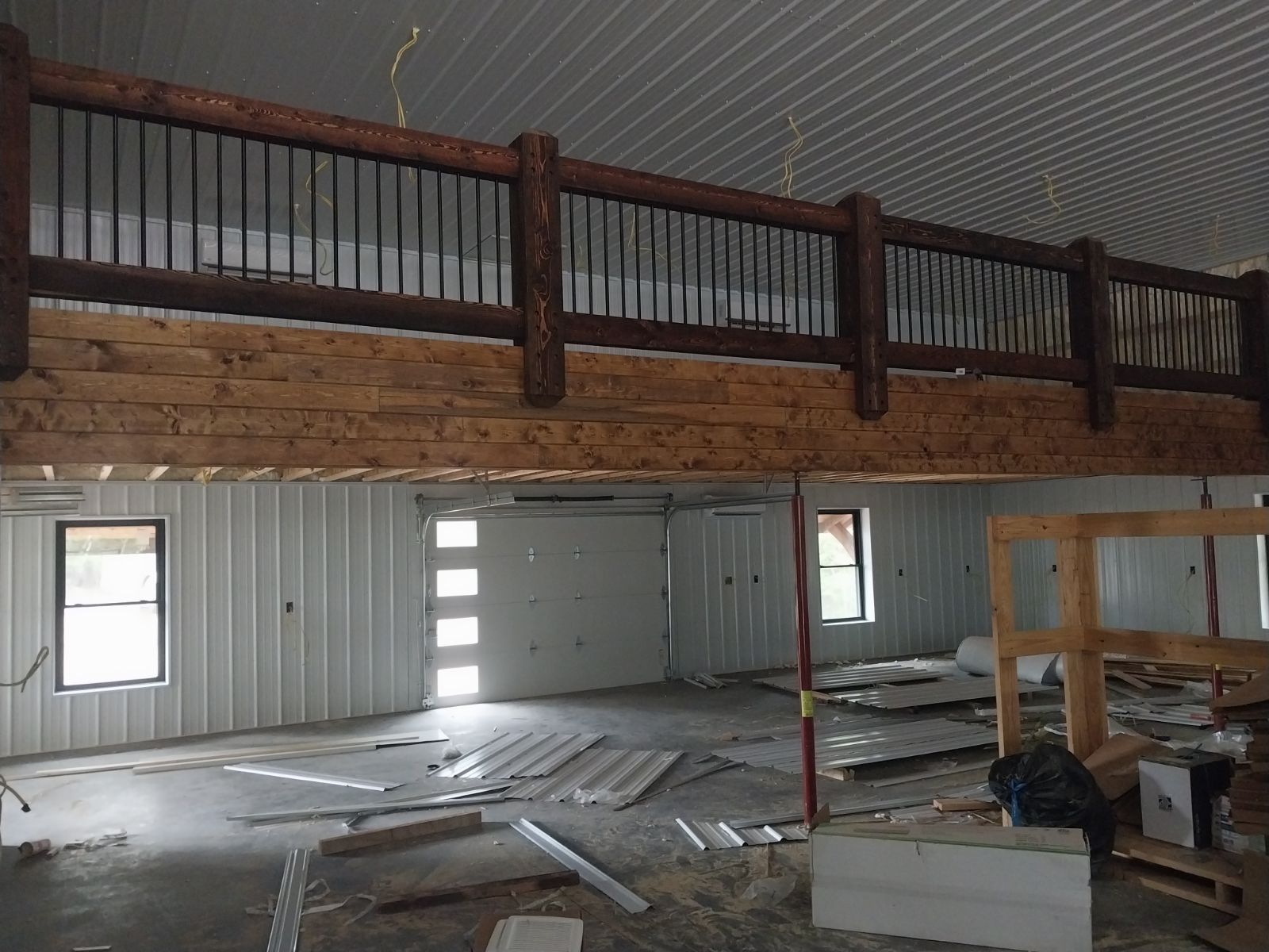 Interior view of a building under construction with a wooden balcony and metal walls.