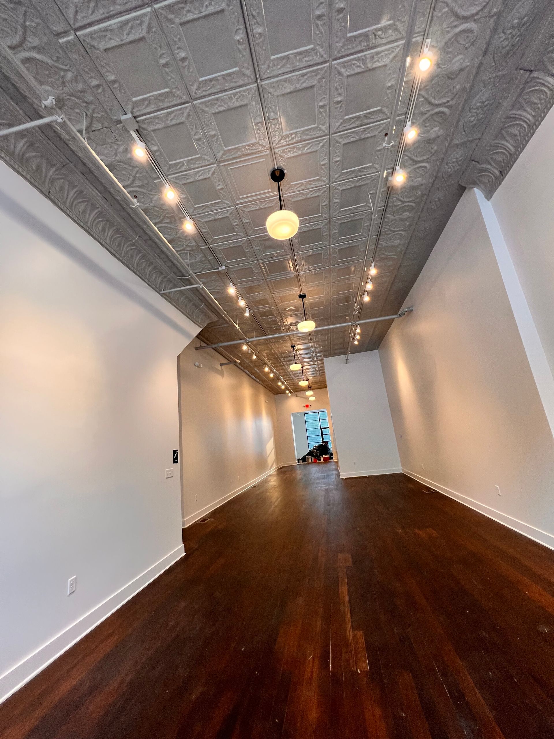 An empty room with a tiled ceiling and wooden floors