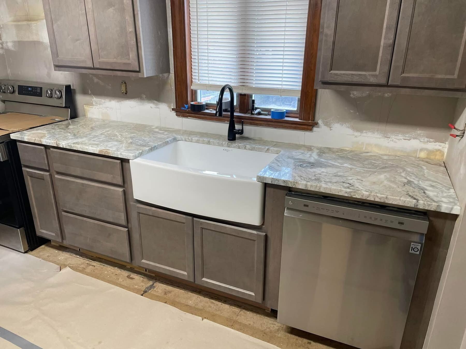A kitchen with stainless steel appliances and a white farmhouse sink.