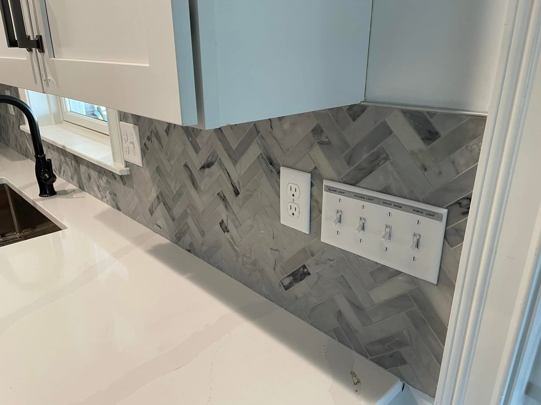 A kitchen with a sink , faucet , and electrical outlets.