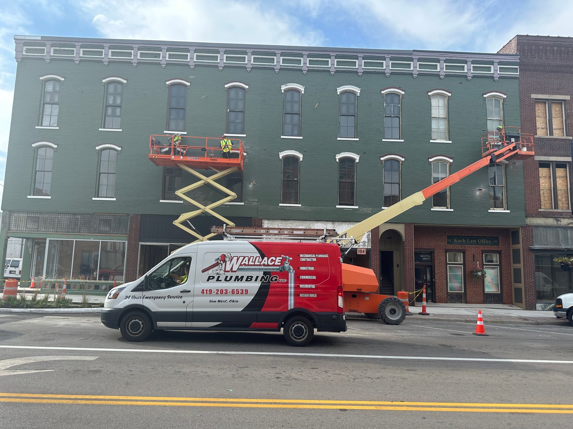 A plumber van is parked in front of a building