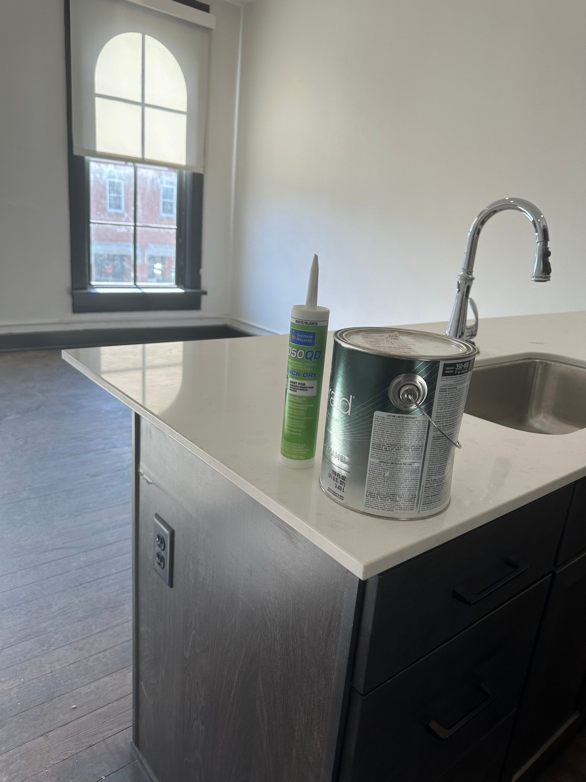 A kitchen with a sink and a can of paint on the counter