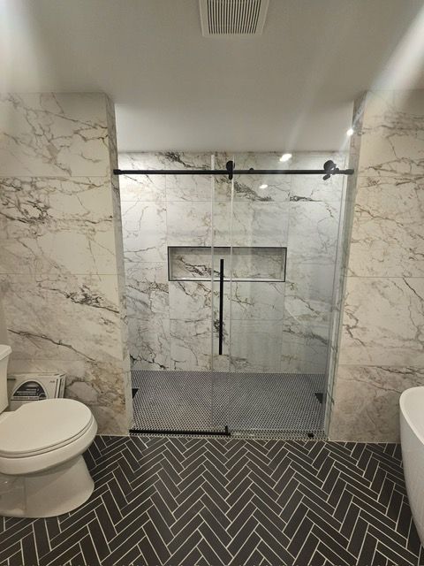 A bathroom with a toilet , shower and bathtub.