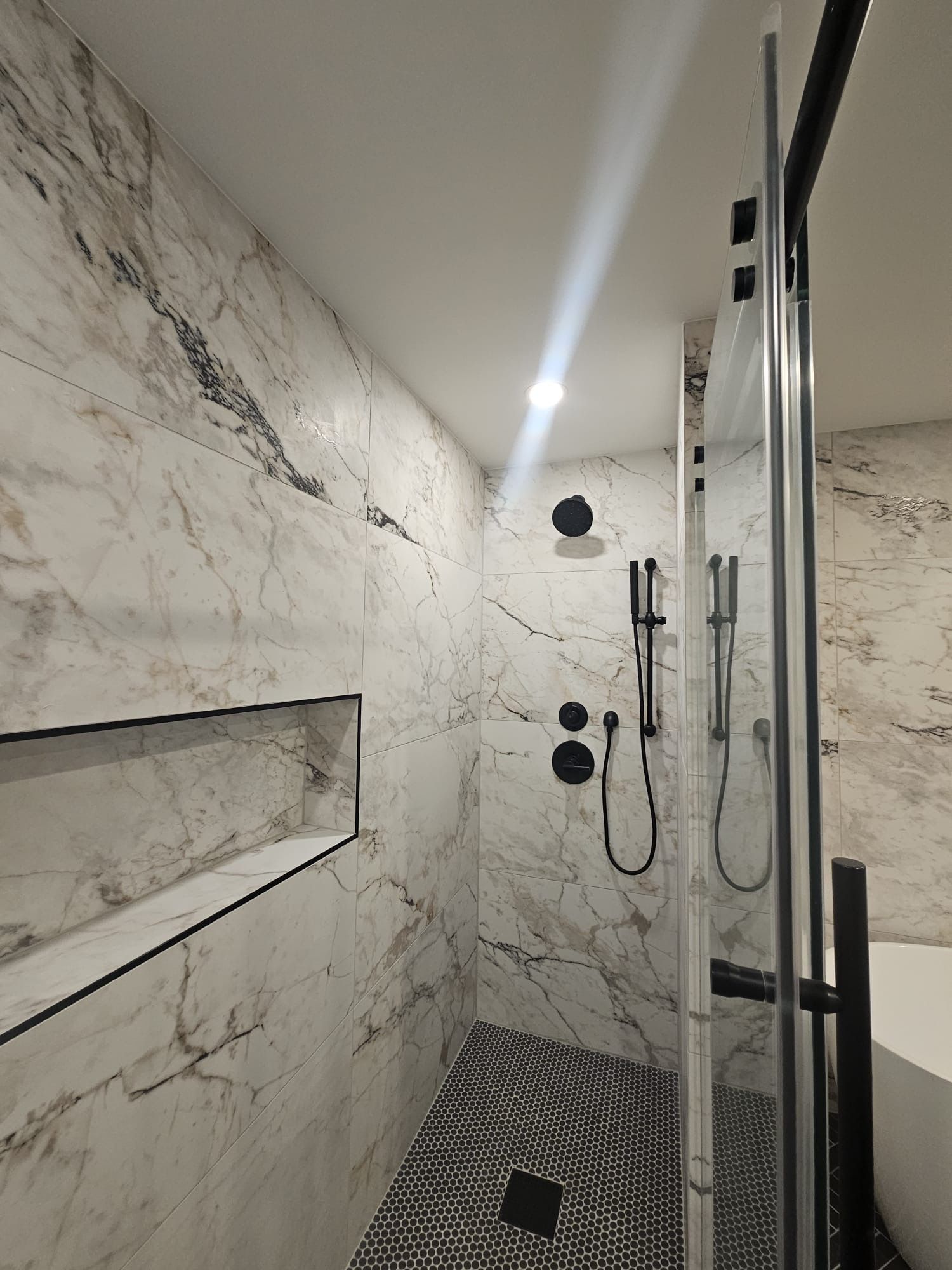 A bathroom with marble walls and a walk in shower.