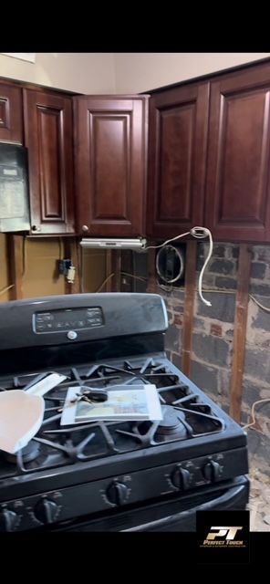 A black stove top oven is sitting in a kitchen with wooden cabinets.