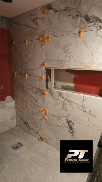 A bathroom is being remodeled with marble tiles and a window.