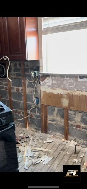 A kitchen with a stove and a window being remodeled.