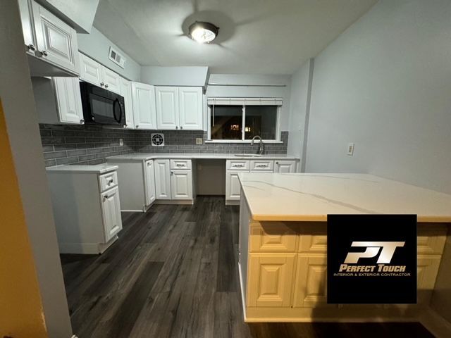A kitchen with white cabinets and a pt logo on the counter