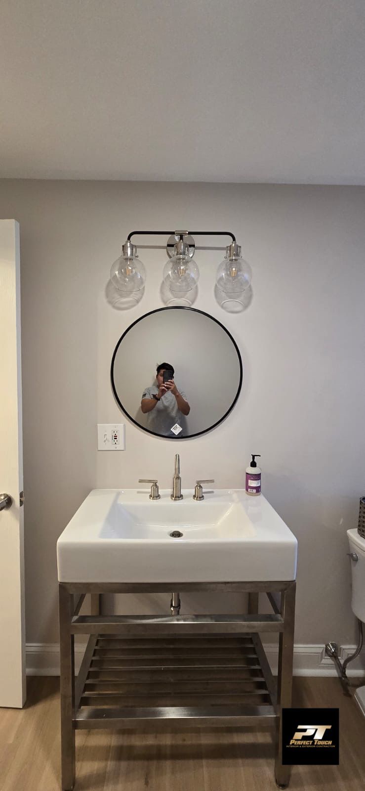 A bathroom with a sink , mirror and light fixture.