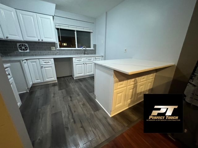 A kitchen with white cabinets and a large island.