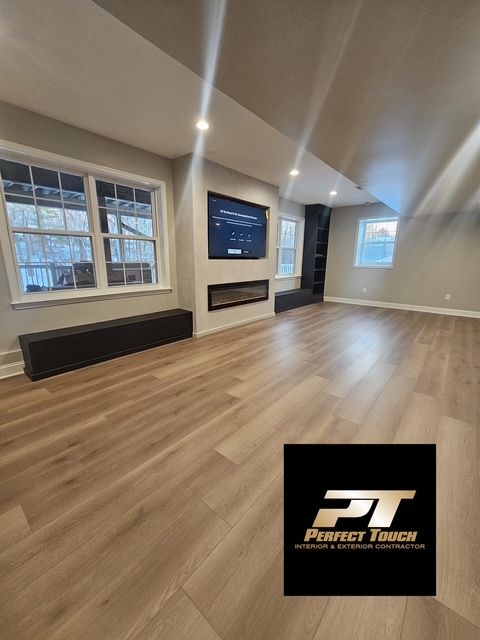 A living room with hardwood floors and a tv mounted on the wall.