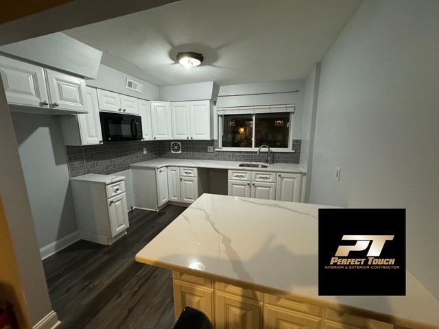 A kitchen with white cabinets and a white counter top.