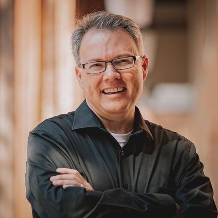 A woman in a green shirt is laughing with her mouth open
