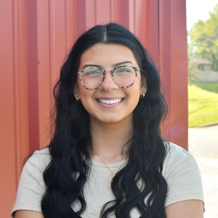 A woman in a green shirt is laughing with her mouth open