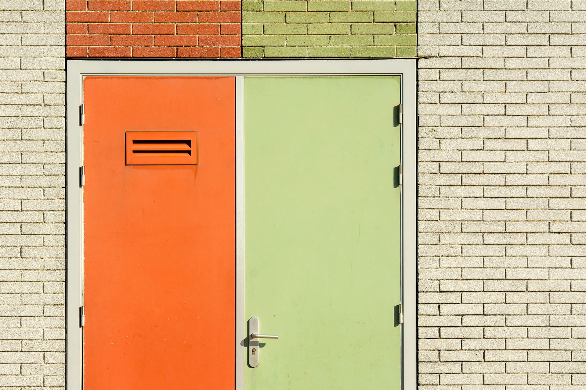 Orange and green doors, with brick wall.