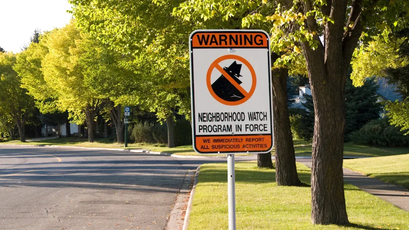 Neighborhood watch sign with a bear crossed out, near trees.