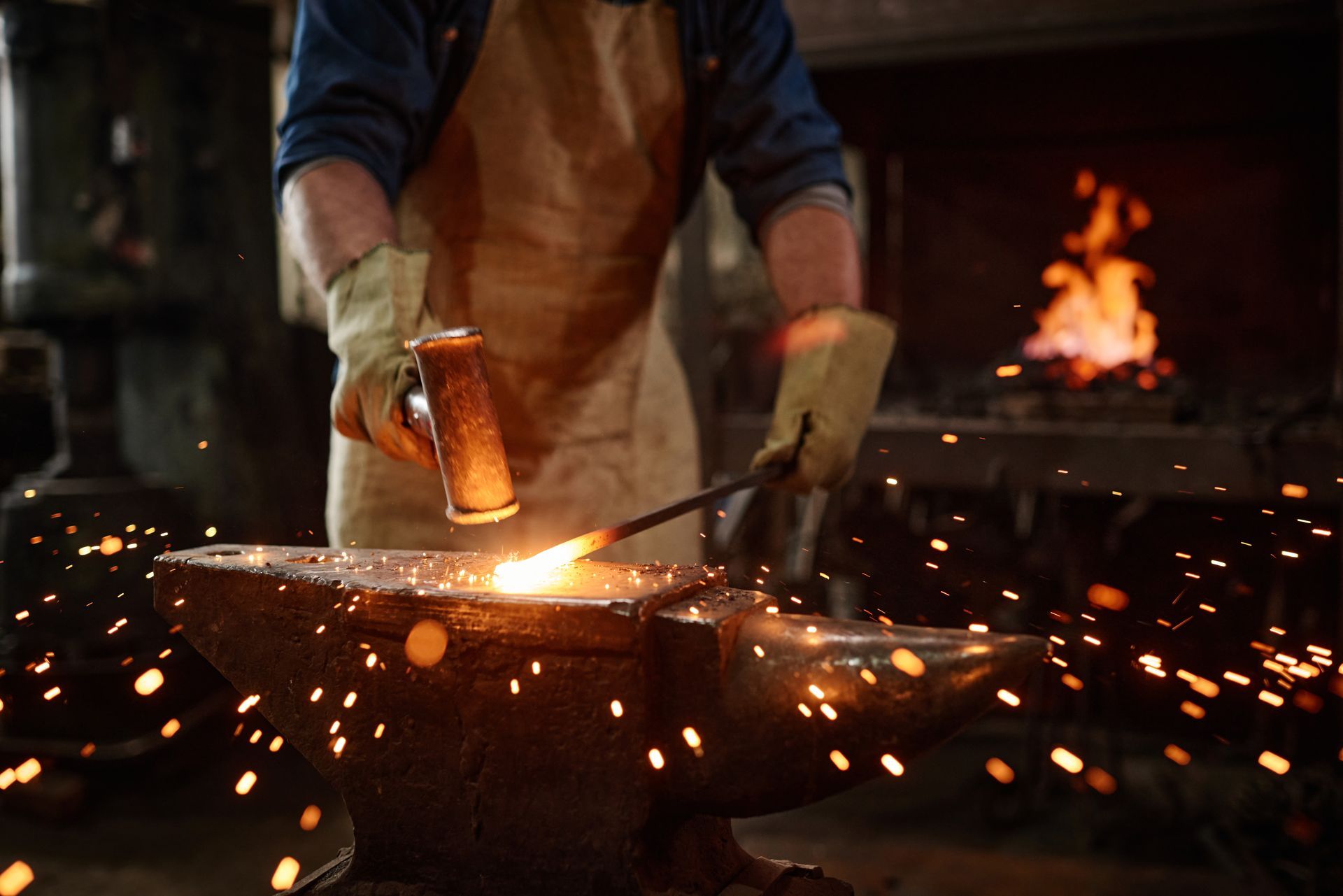 A blacksmith is working on a piece of metal on an anvil.