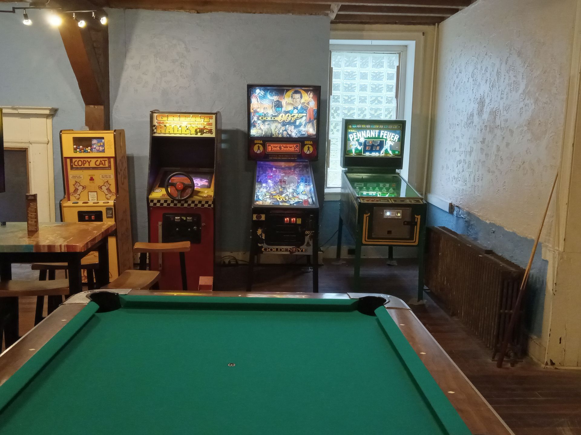 A pool table in a room with pinball machines