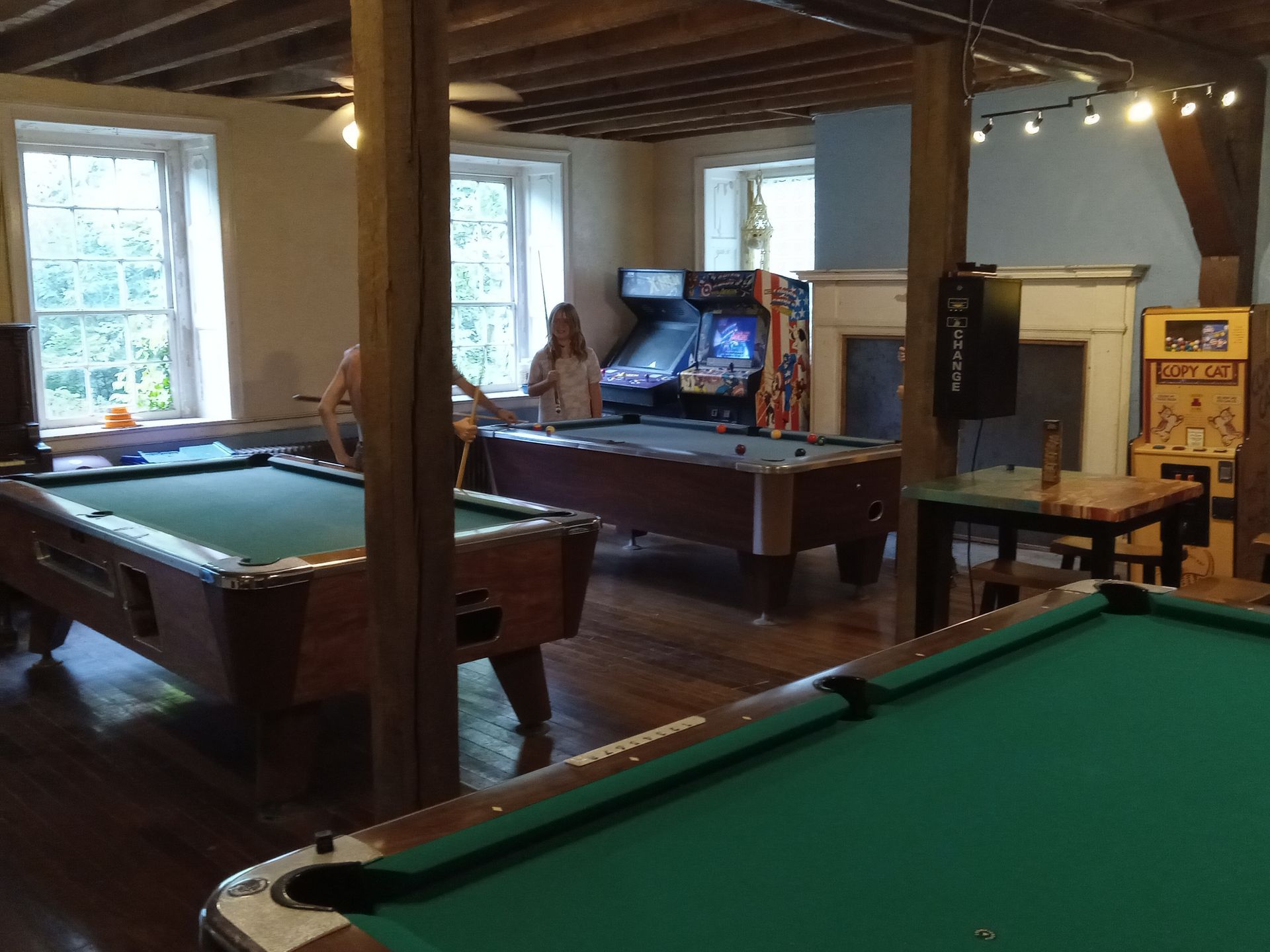 A room with pool tables and an arcade machine