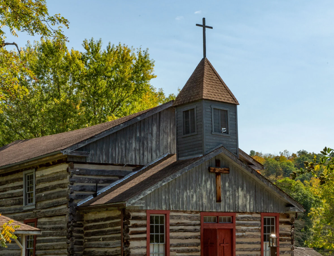 An old wooden church with a cross on top of it.