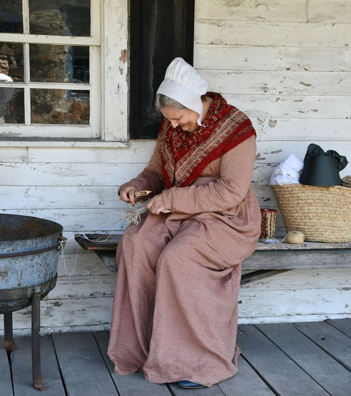 A woman in a pink dress is sitting on a porch