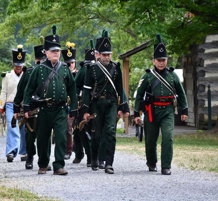 A group of men in military uniforms are marching down a dirt road