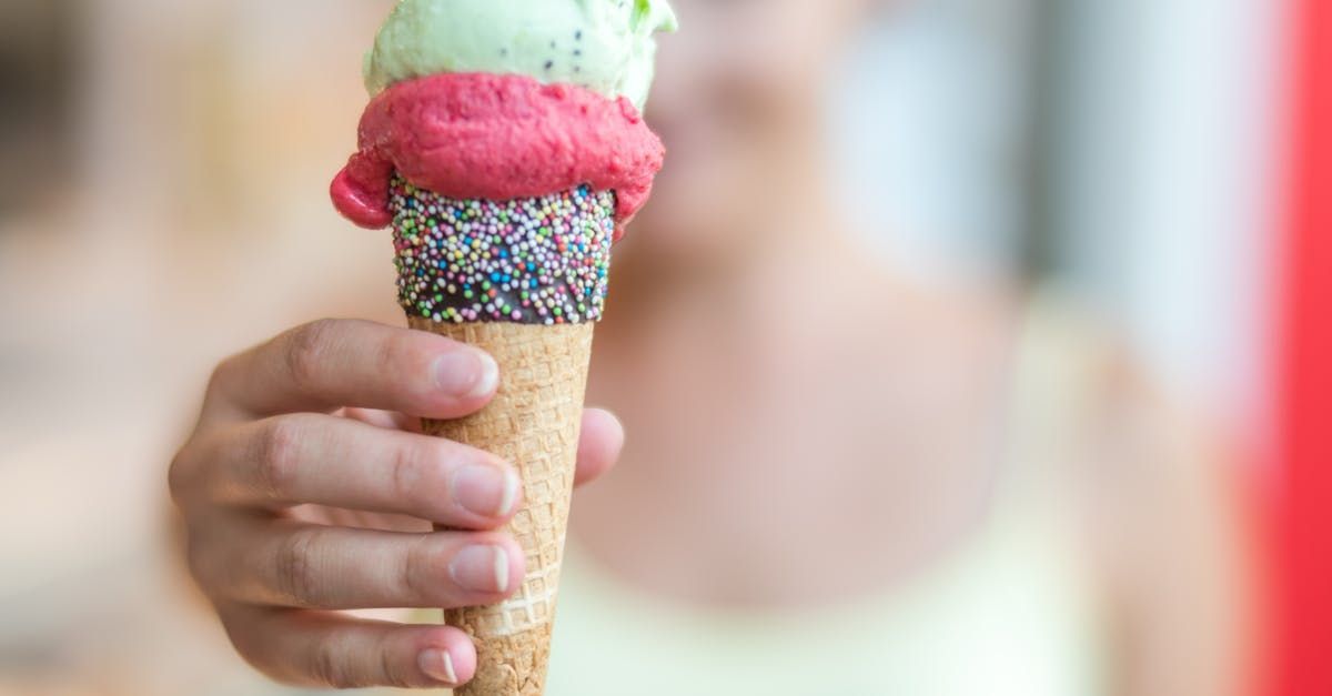 A person is holding two scoops of ice cream in a waffle cone.