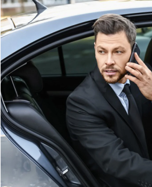 Man in blue suit opens car door for person inside.