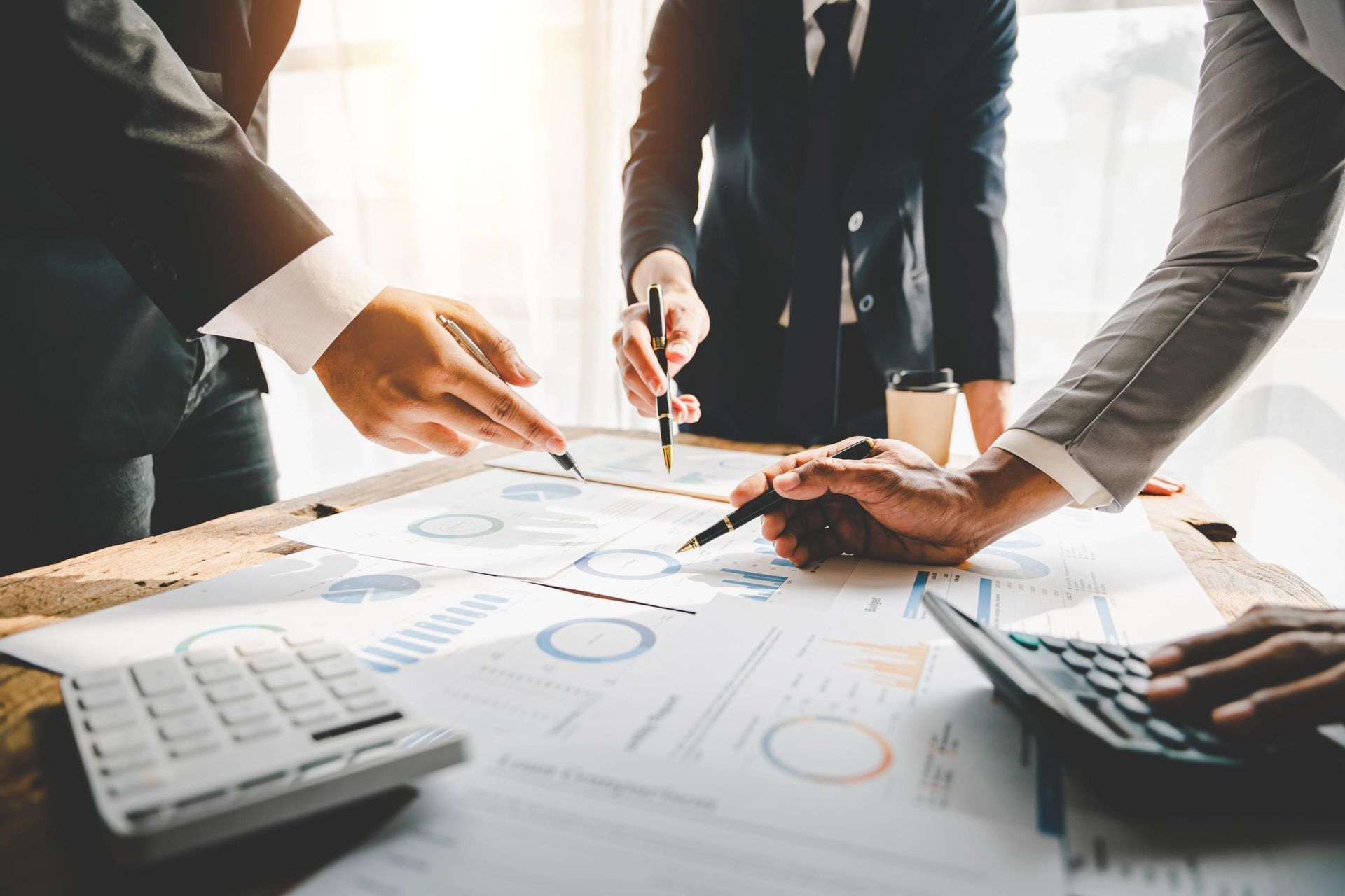 A group of business people are sitting around a table looking at charts and graphs.