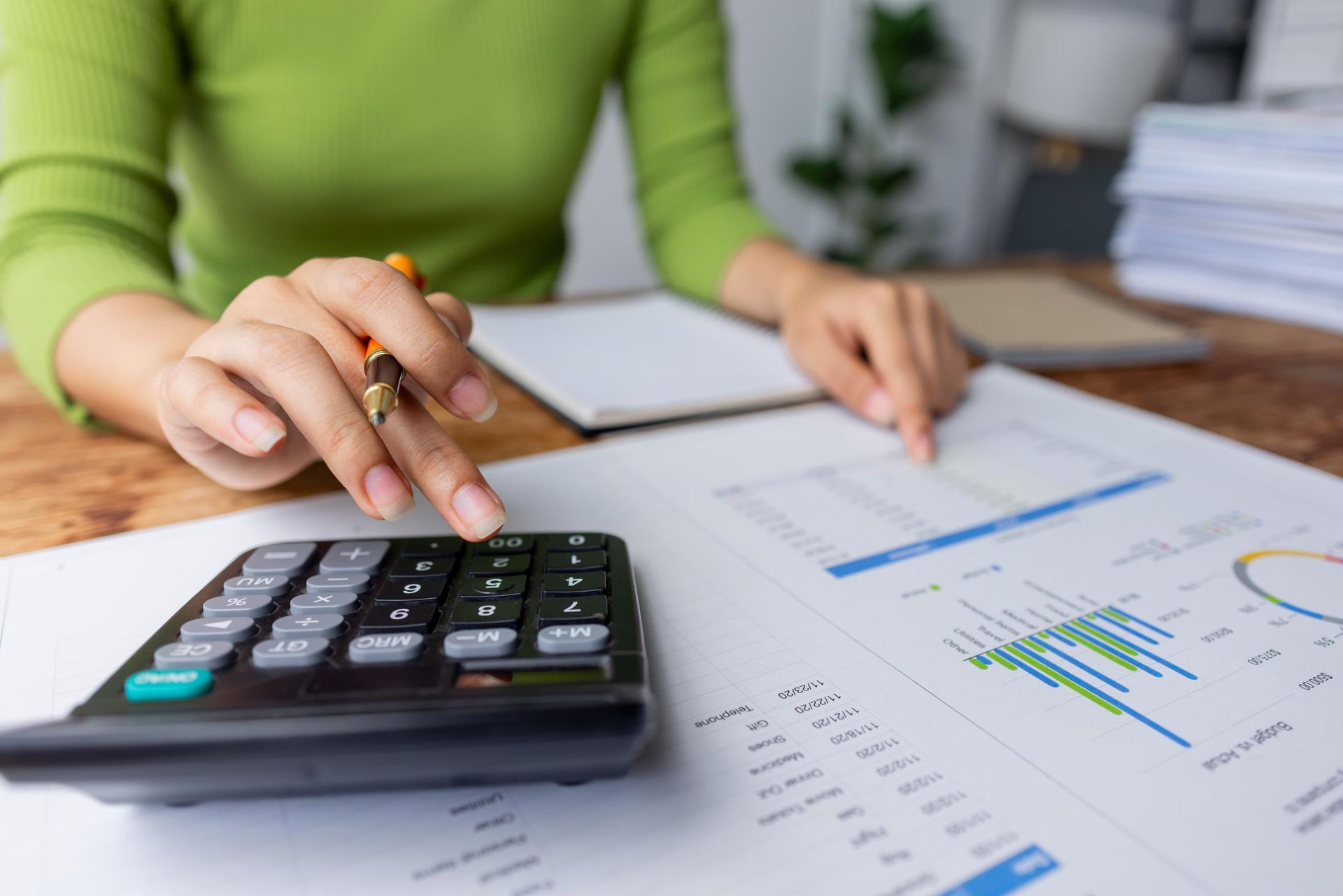 A woman is sitting at a table using a calculator.