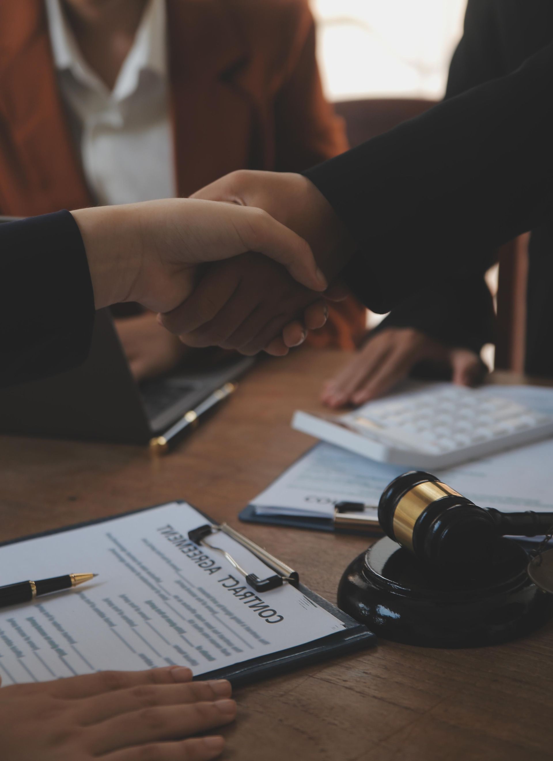 A woman is shaking hands with another woman while sitting at a table.