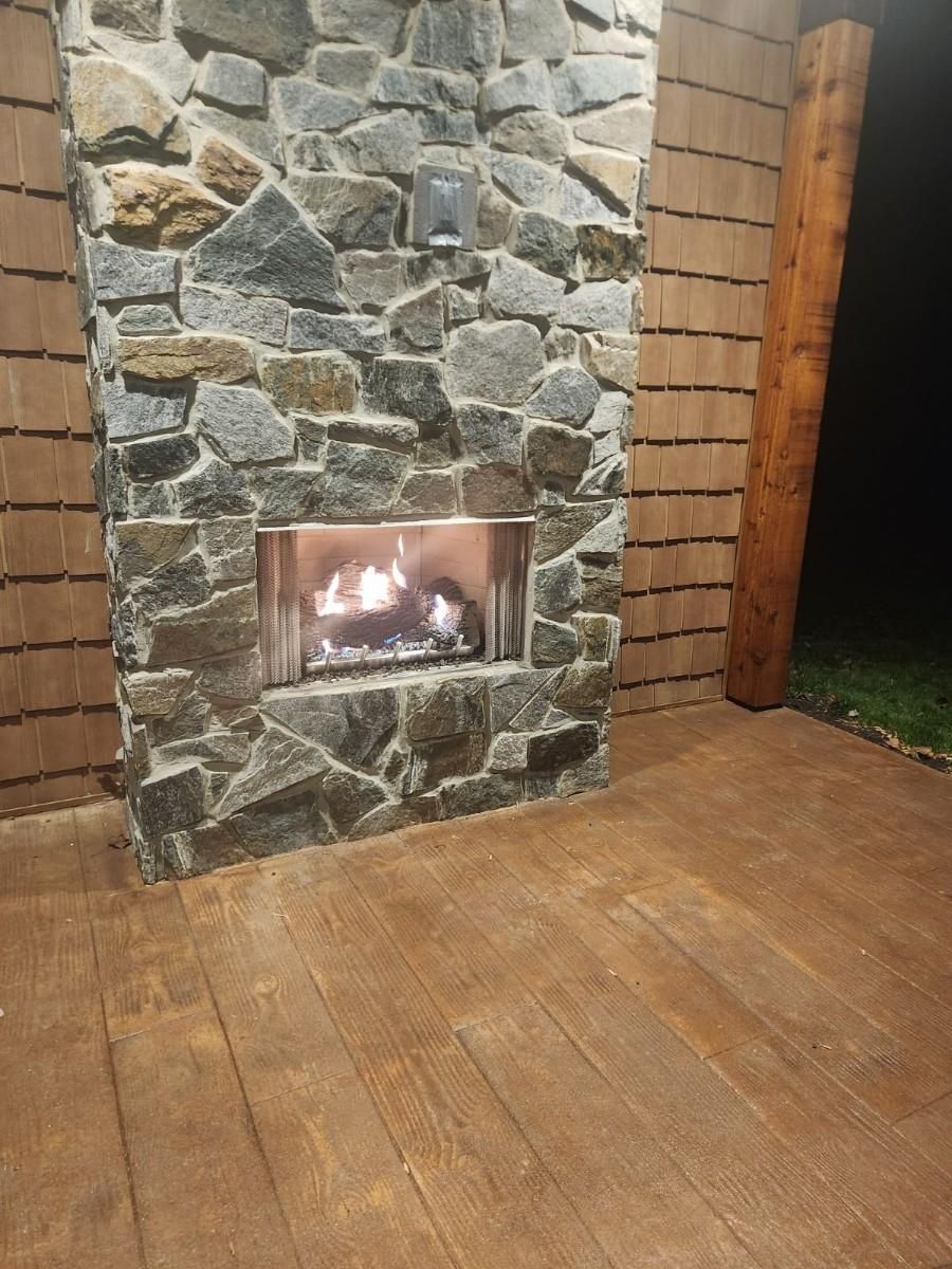 There is a fireplace in the middle of a stone wall. — Glen Burnie, MD — McAllister Plumbing Inc.