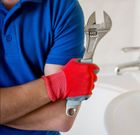 A man wearing red gloves is holding a wrench