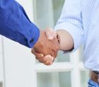 A man and a woman are shaking hands in front of a door.