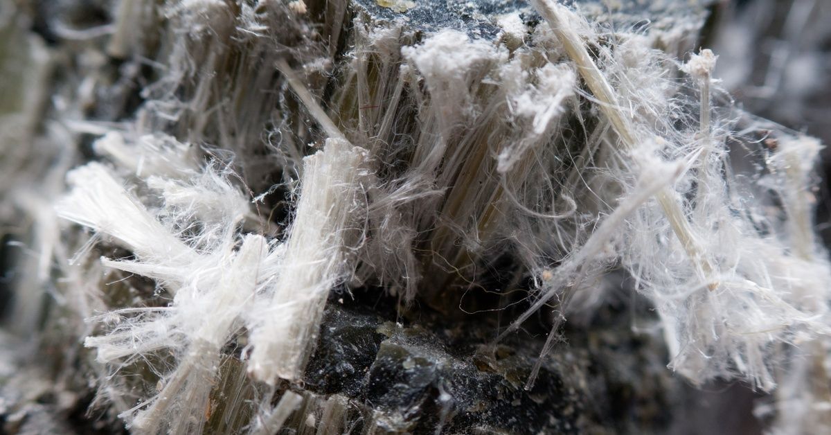 A close-up of white, grey, and black chunks of stringy asbestos fibers.