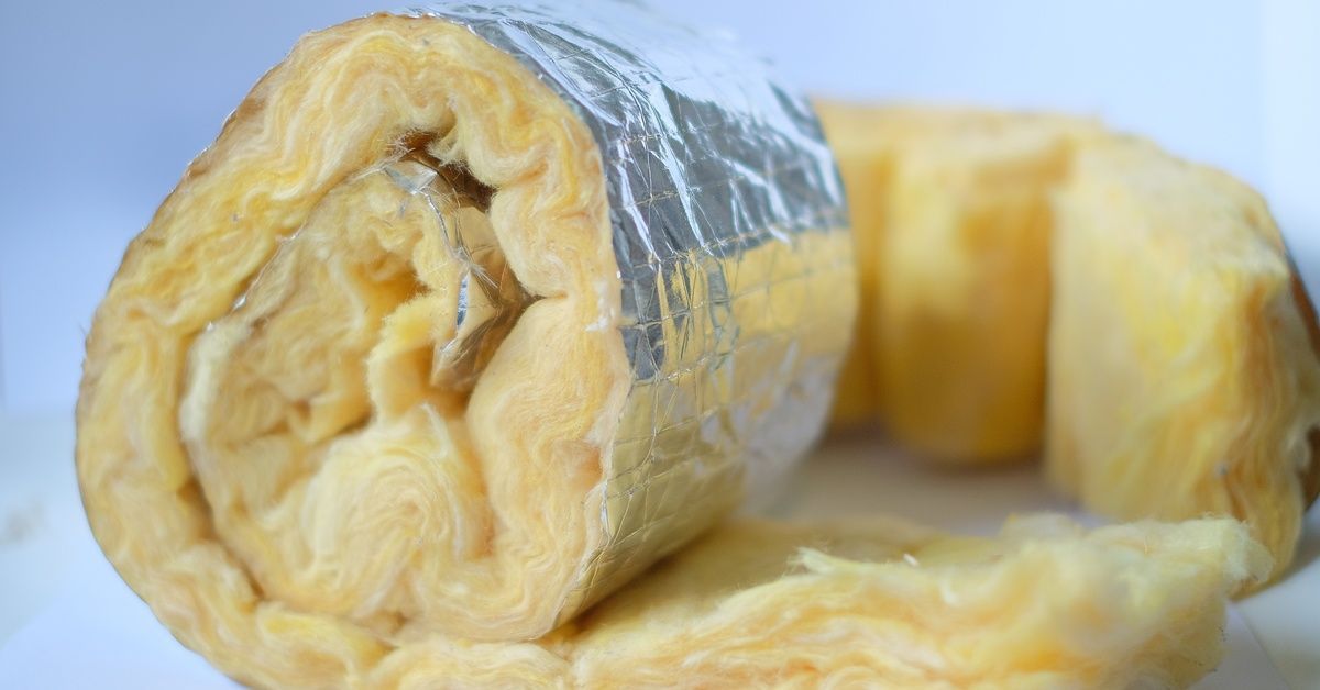 A close-up of a sheet of orange insulation attached to a silver lining. It is rolled up.