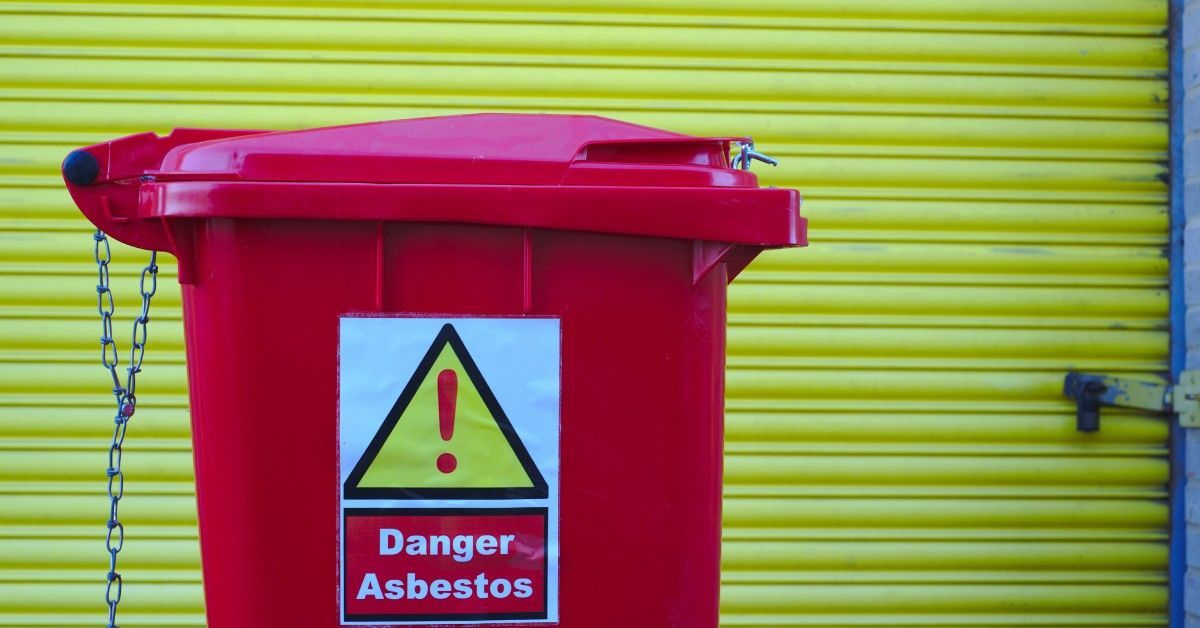 A bright red garbage bin with a sign on it that says,