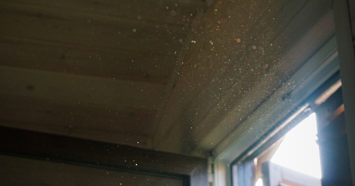 A bright beam of sunlight enters through a window, highlighting floating dust particles in a dark ro