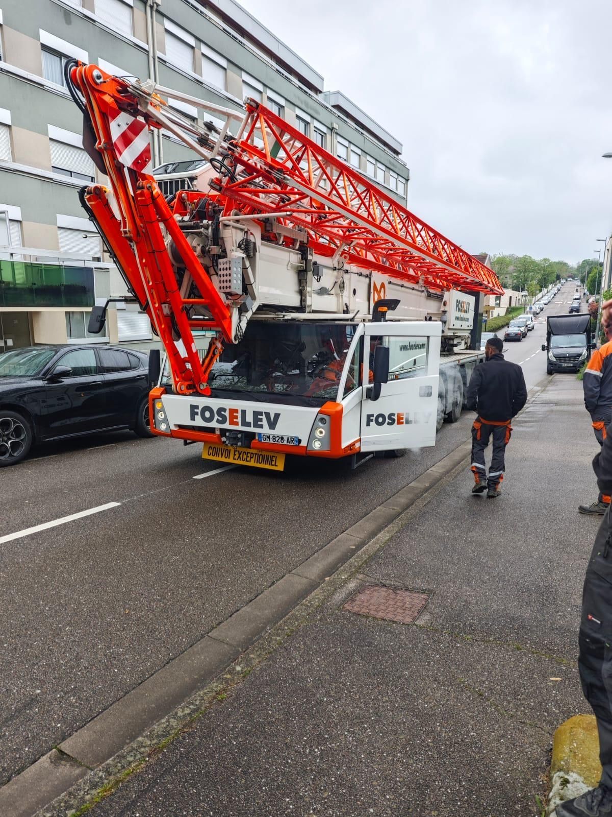 Une grue est garée sur le bord de la route à côté d'un bâtiment.