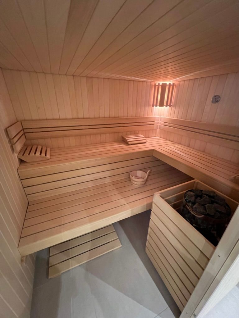 Un sauna en bois avec un seau et un poêle.