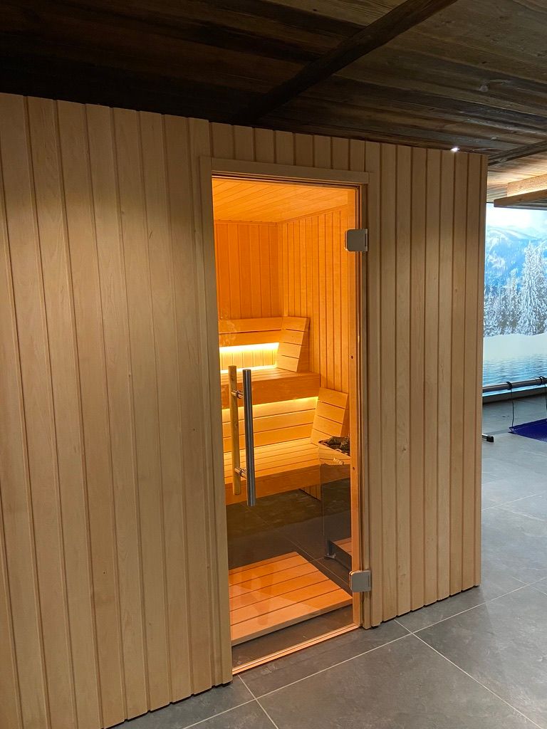Un sauna en bois avec une porte vitrée et des escaliers.